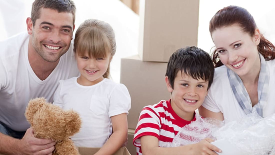 Family of four unpacking boxes and bubble wrap in their new home